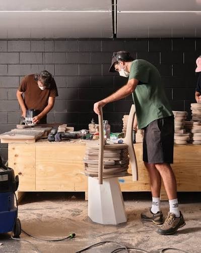 Two of the team working at a bench in the workshop with dust extraction running