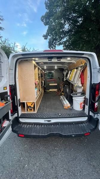 The back of the work van fitted out with shelving, tools and coating supplies