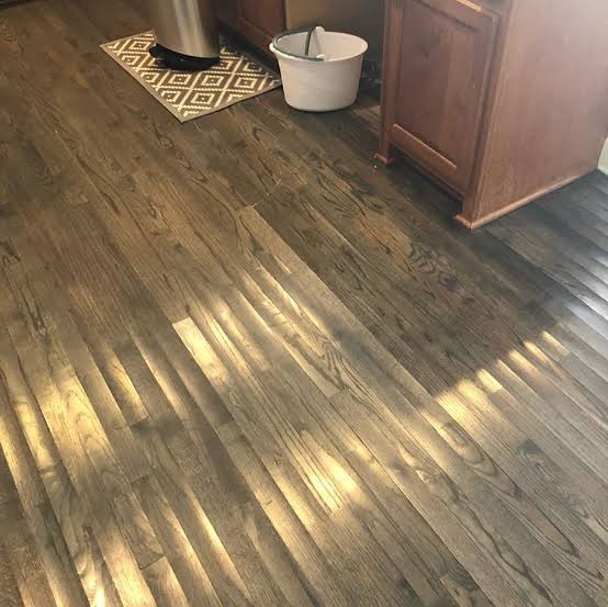 Cupping visible in a timber floor, board edges sitting higher than their centres under raking light