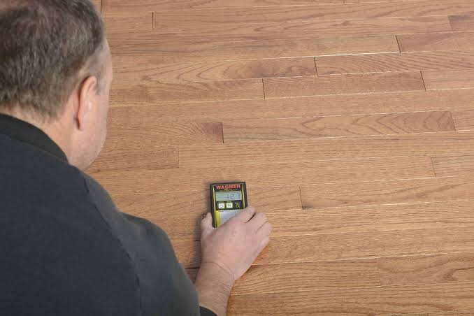Pin-type moisture meter taking a reading in a timber floorboard