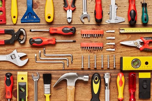 Hand tools laid out in rows on a timber workbench, viewed from above
